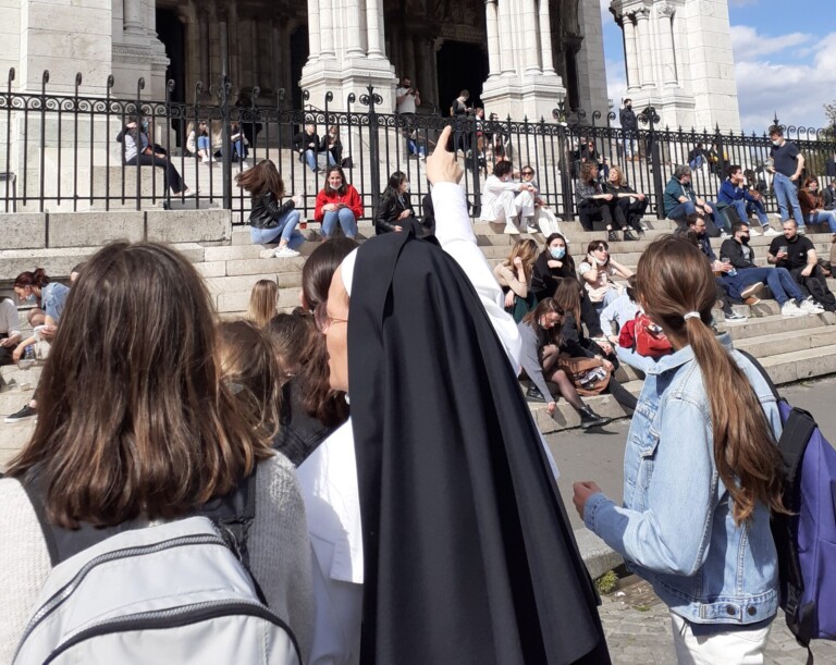 Soeur bénédictine sur le parvis de la basilique parlant avec des jeunes filles